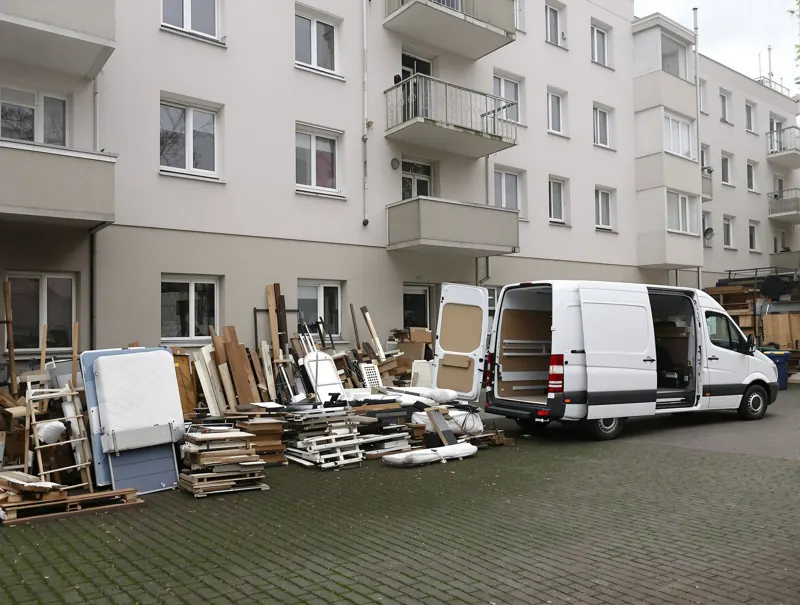 Sortierte Möbel und Sperrmüll im Hof eines Leipziger Wohnhauses neben einem Transporter